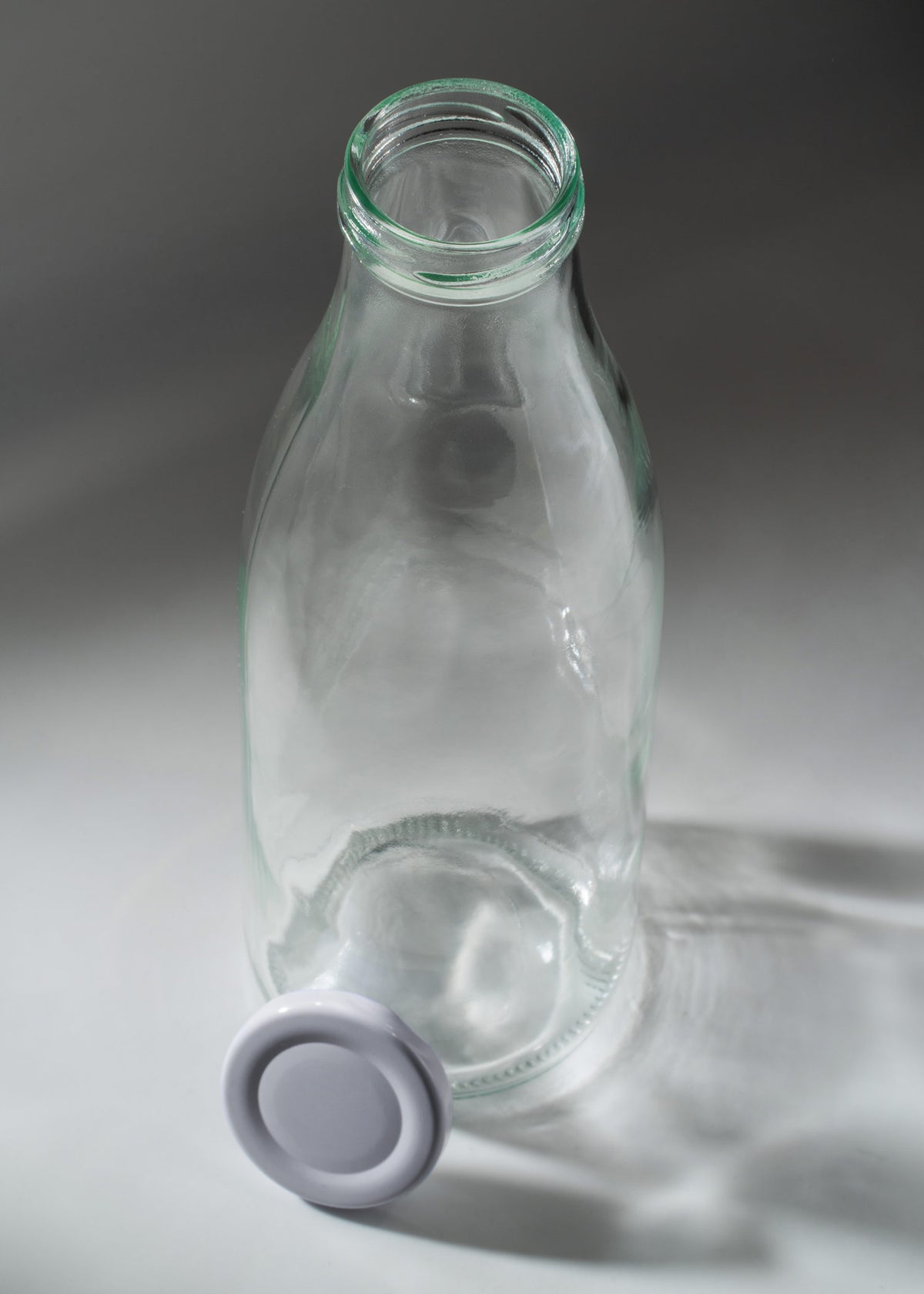 Vista superior de la botella Milky de 950 ml abierta con su tapa blanca junto al envase.