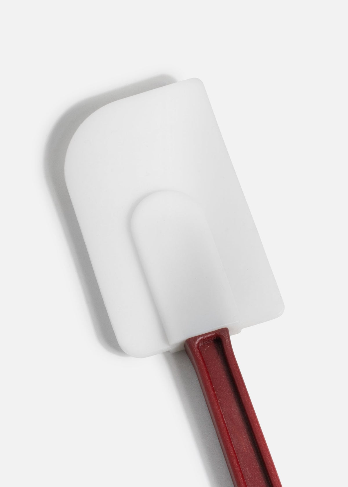 Detalle de la pala blanca de silicón y su unión con el mango rojo de la espátula miserable para repostería.