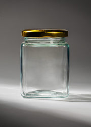 Frasco cuadrado de vidrio transparente de 200 ml con tapa de rosca dorada, vista completa.