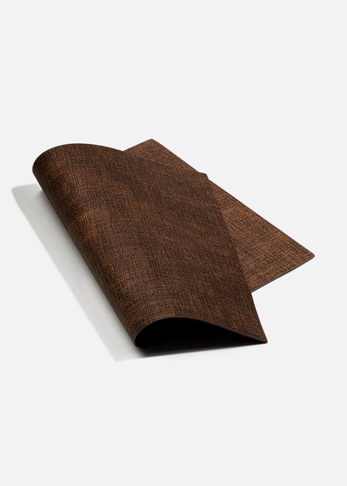 Mantel individual de vinilo café parcialmente enrollado para mostrar su flexibilidad.