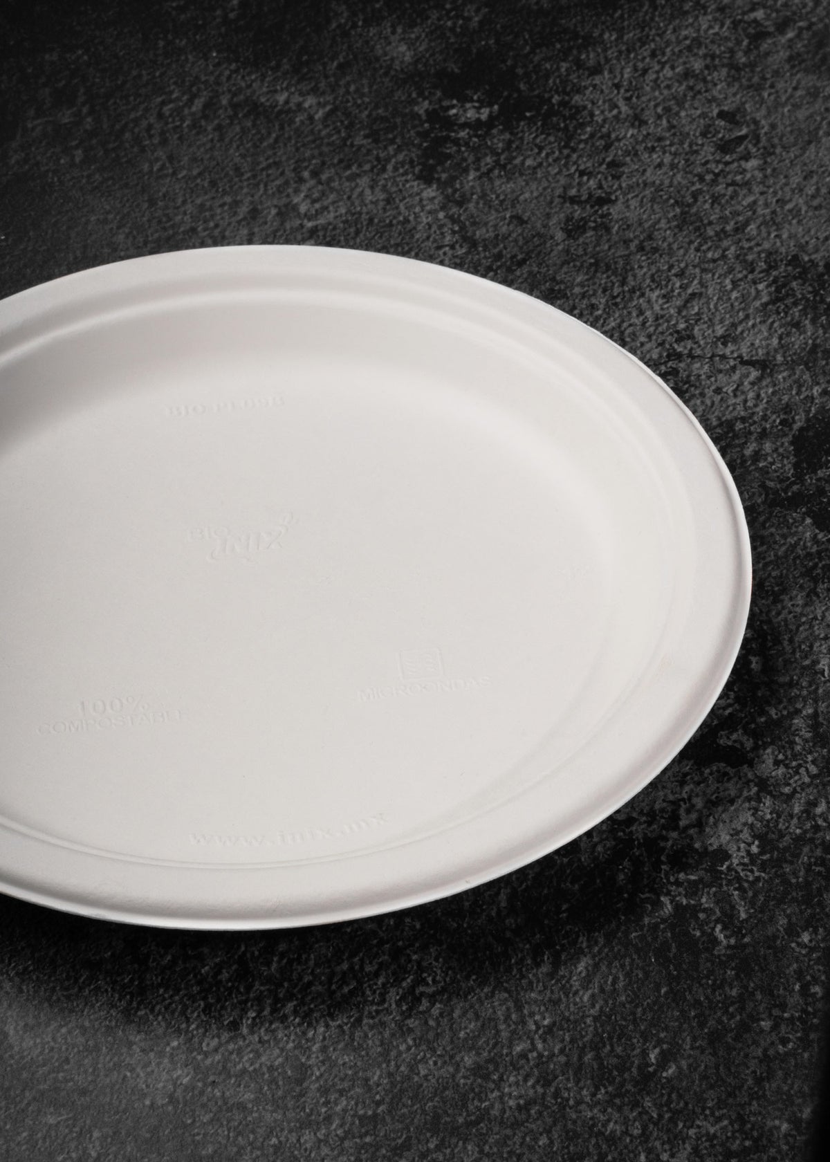 Detalle del reverso y el borde del plato compostable blanco de bagazo de caña y maíz.