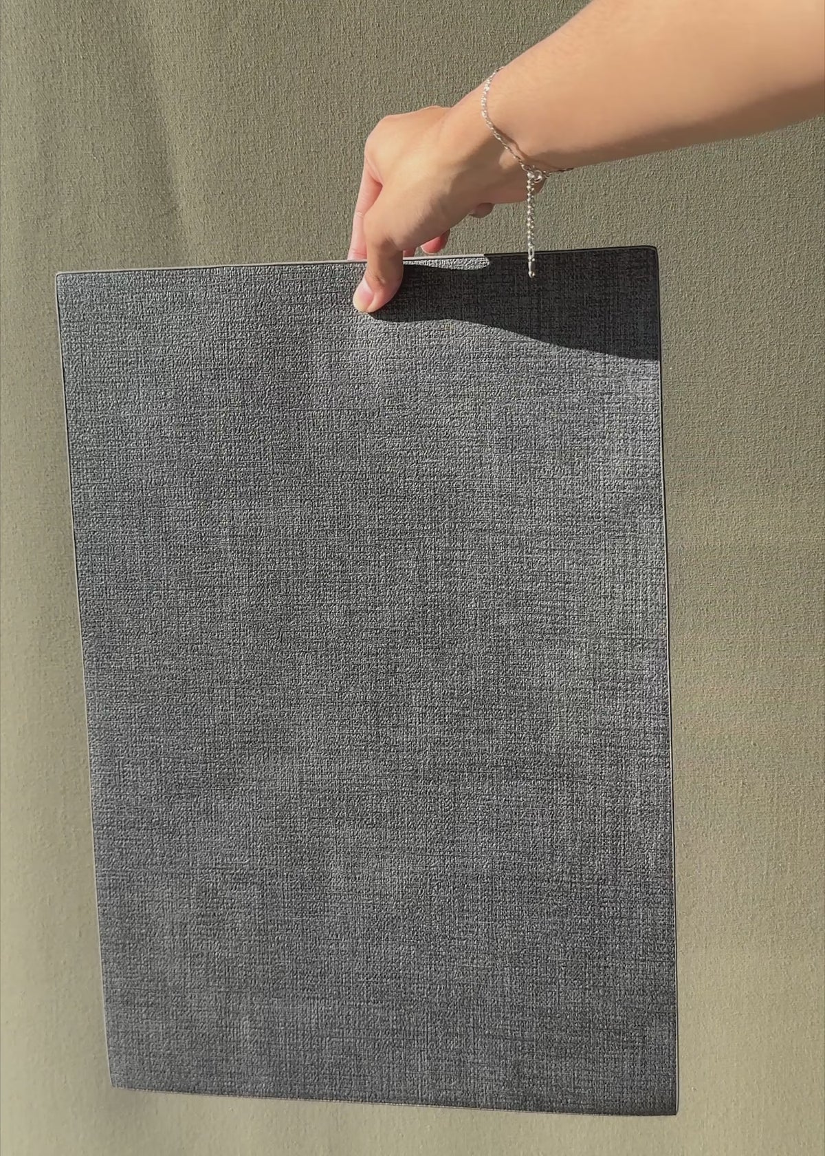 Cargar vídeo: Video en luz natural del mantel individual de vinilo gris oscuro que muestra su textura y flexibilidad.