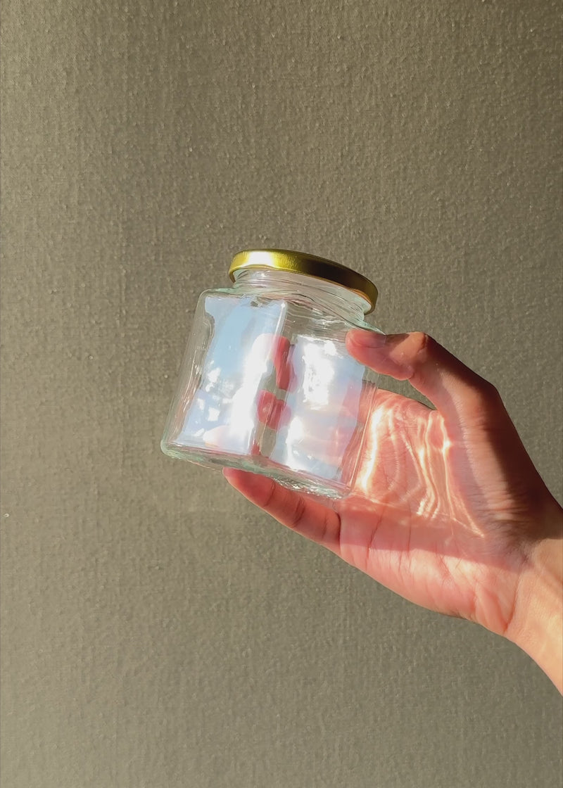 Video con luz natural del frasco de vidrio transparente con tapa dorada de 200 ml.