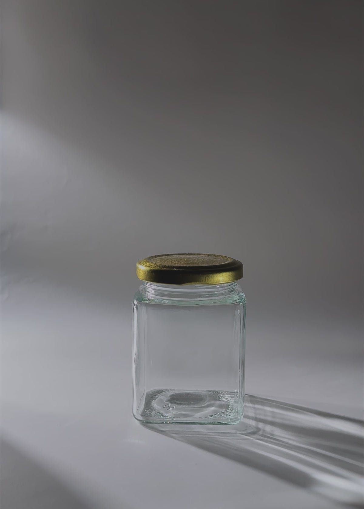 Cargar vídeo: Video de estudio del frasco cuadrado de vidrio de 200 ml con tapa dorada.