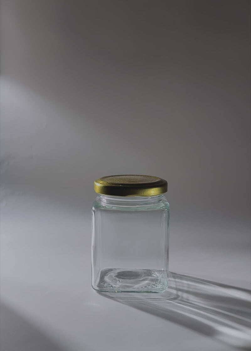 Video de estudio del frasco cuadrado de vidrio de 200 ml con tapa dorada.