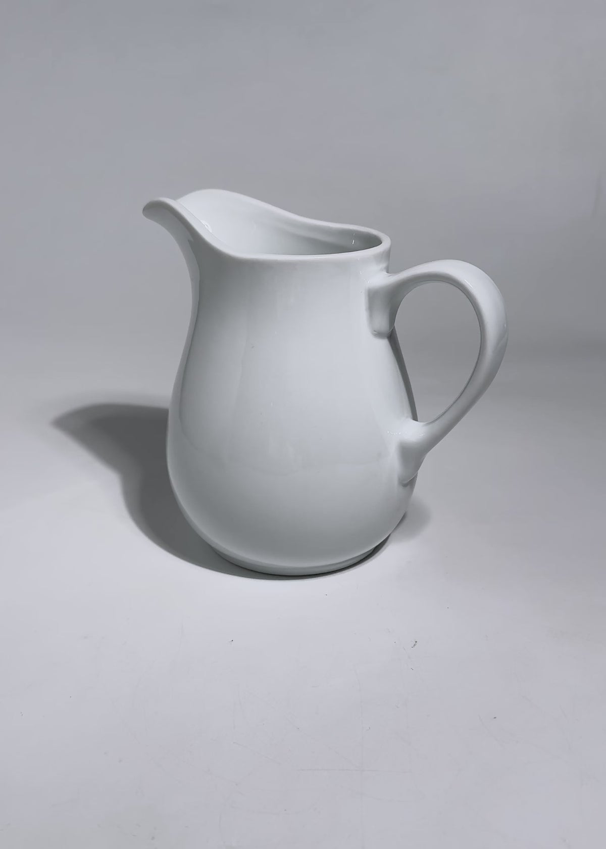 Cargar vídeo: Video de estudio de jarra lechera blanca de porcelana con asa y pico vertedor.