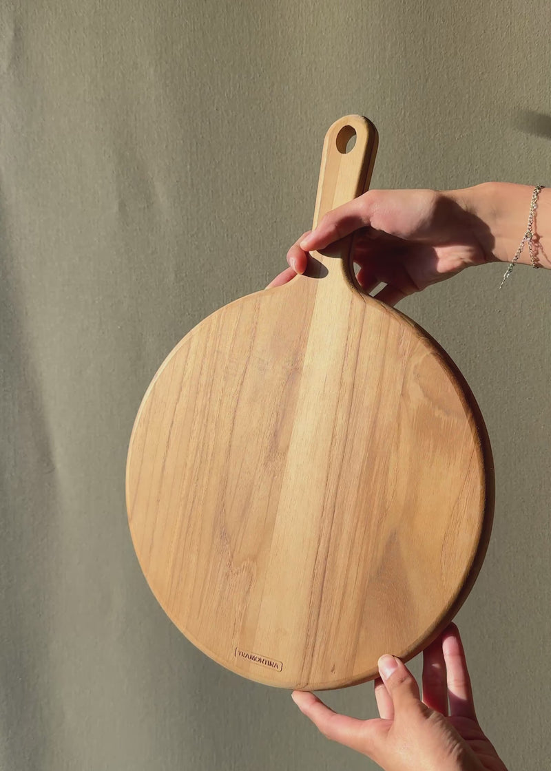 Video con luz natural de tabla para pizza de teca café con mango.
