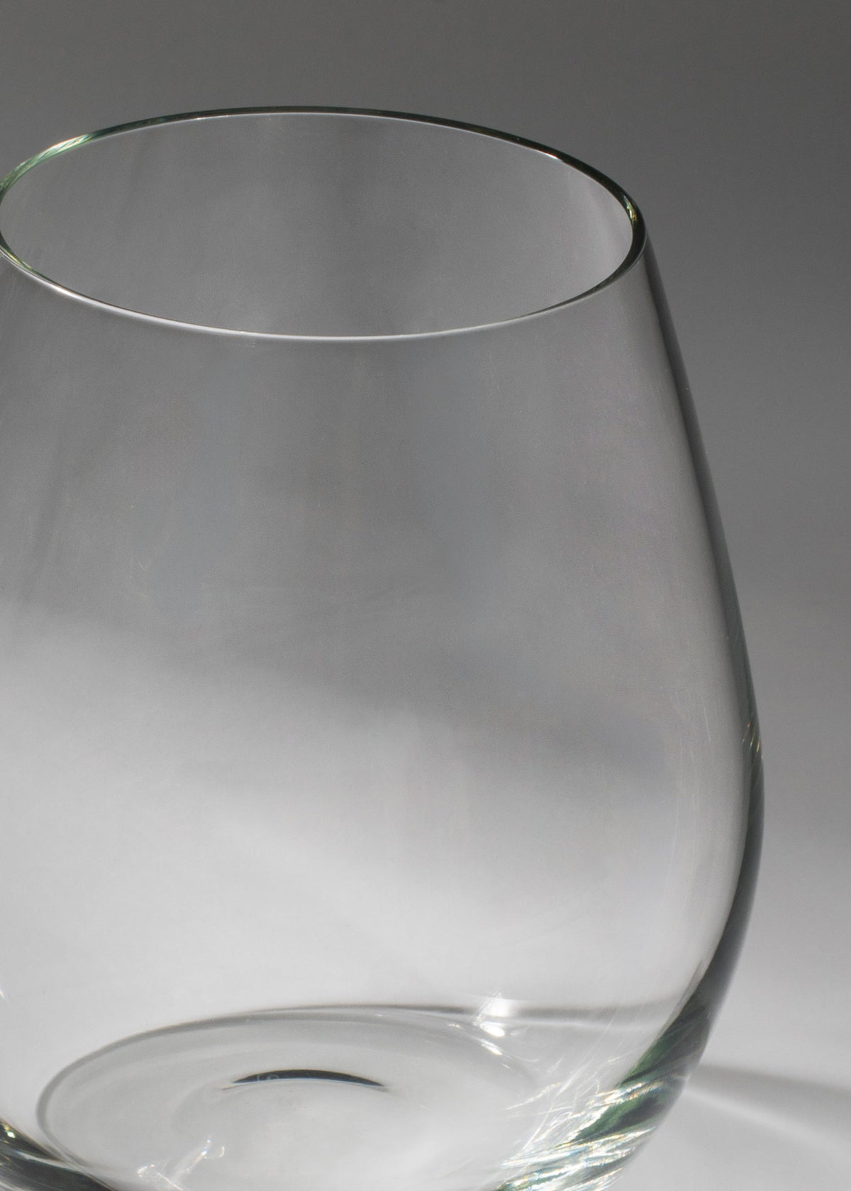 Detalle del borde y paredes lisas del vaso de vidrio sin tallo para vino tinto.